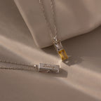 The Duo Birthstone Name Necklace set includes two silver necklaces: one with a yellow gemstone, the other with a rectangular pendant engraved with Daisy—an ideal personalized gift featuring custom name engraving.