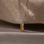 The Duo Birthstone Name Necklace in Sterling Silver features a pendant with one clear and one yellow rectangular gemstone, ideal as personalized jewelry or a unique birthstone name necklace, displayed on a neutral background.
