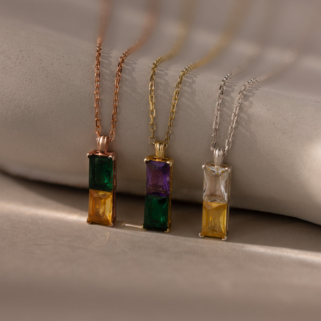 The Duo Birthstone Name Necklace features three gemstone pendants in rose gold, gold, and silver. Personalize each with custom name engraving to create your own unique keepsake.