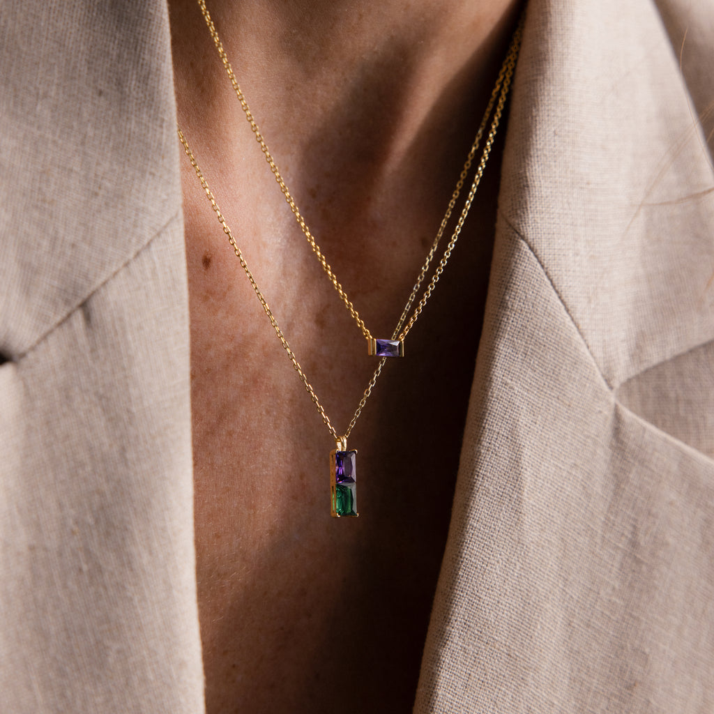 Close-up of a person wearing the Duo Birthstone Name Necklace with vibrant rectangular pendants over a beige blazer—a personalized keepsake featuring custom name engraving.