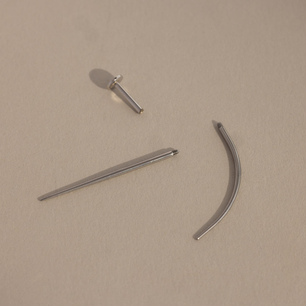 A Flatback Applicator Tool for body piercings rests on a beige background.