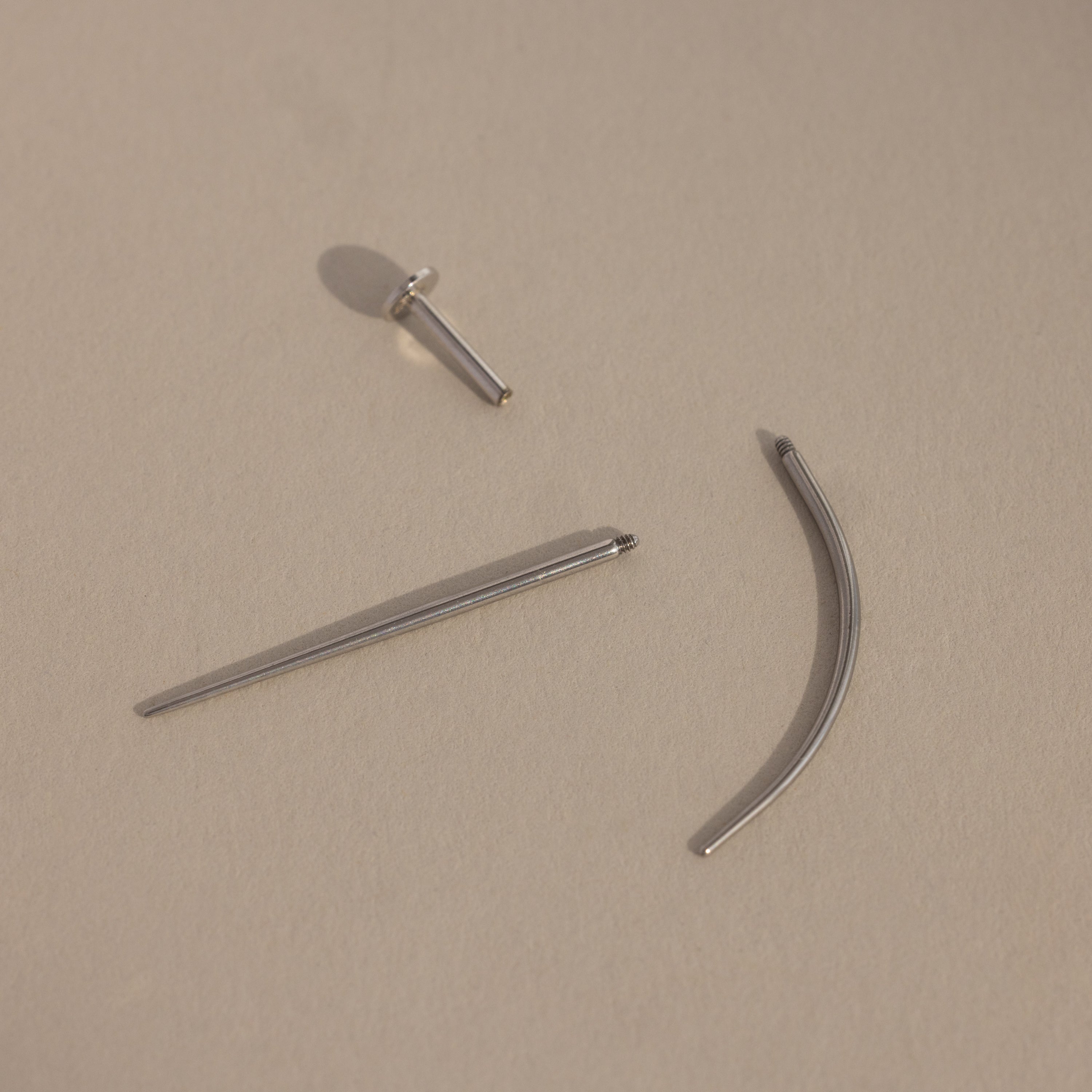 A Flatback Applicator Tool for body piercings rests on a beige background.
