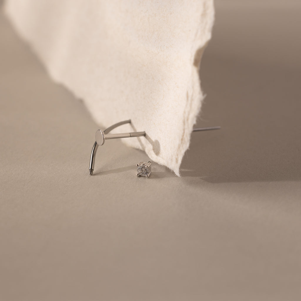 A Flatback Applicator Tool is placed on a beige surface next to torn paper.