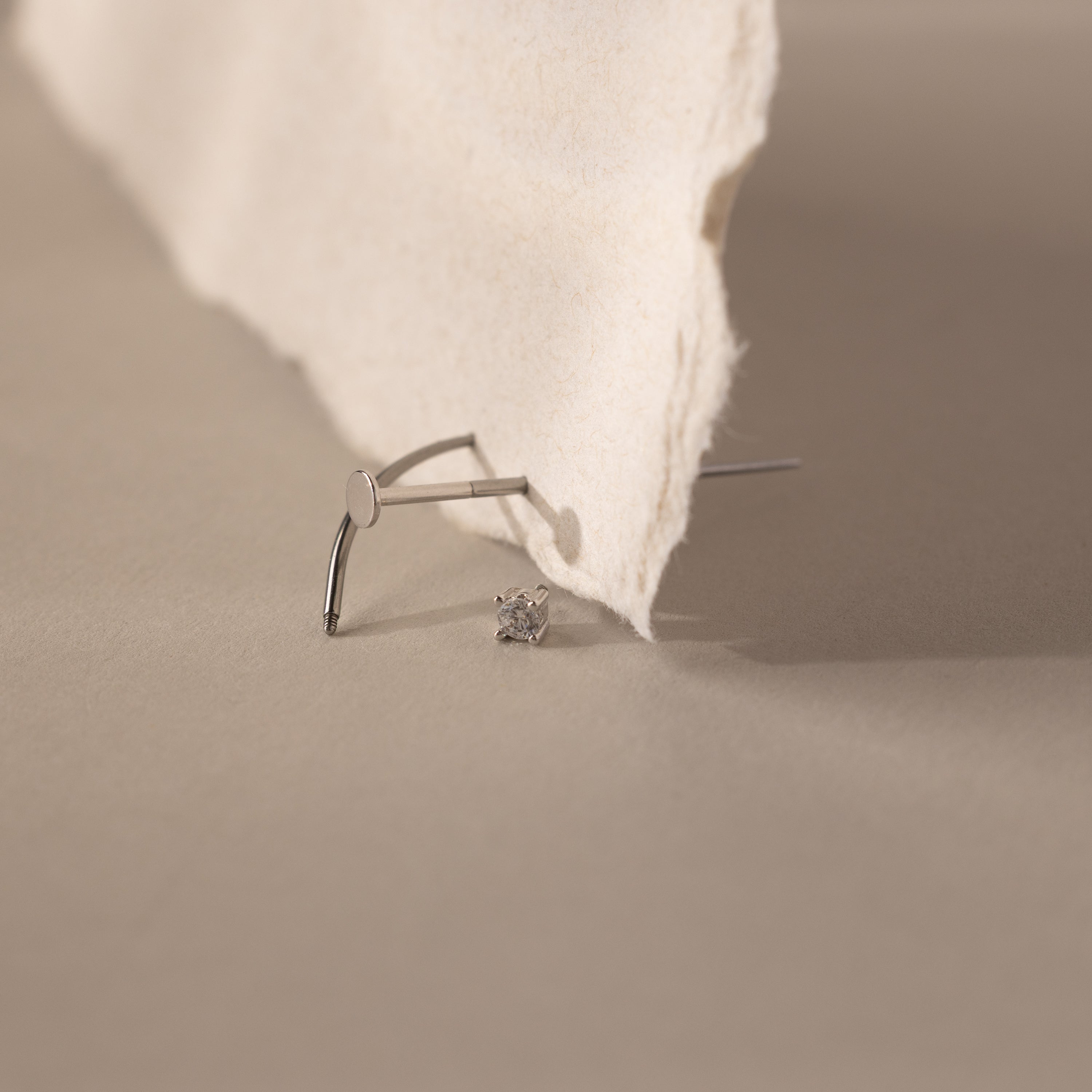 A Flatback Applicator Tool is placed on a beige surface next to torn paper.