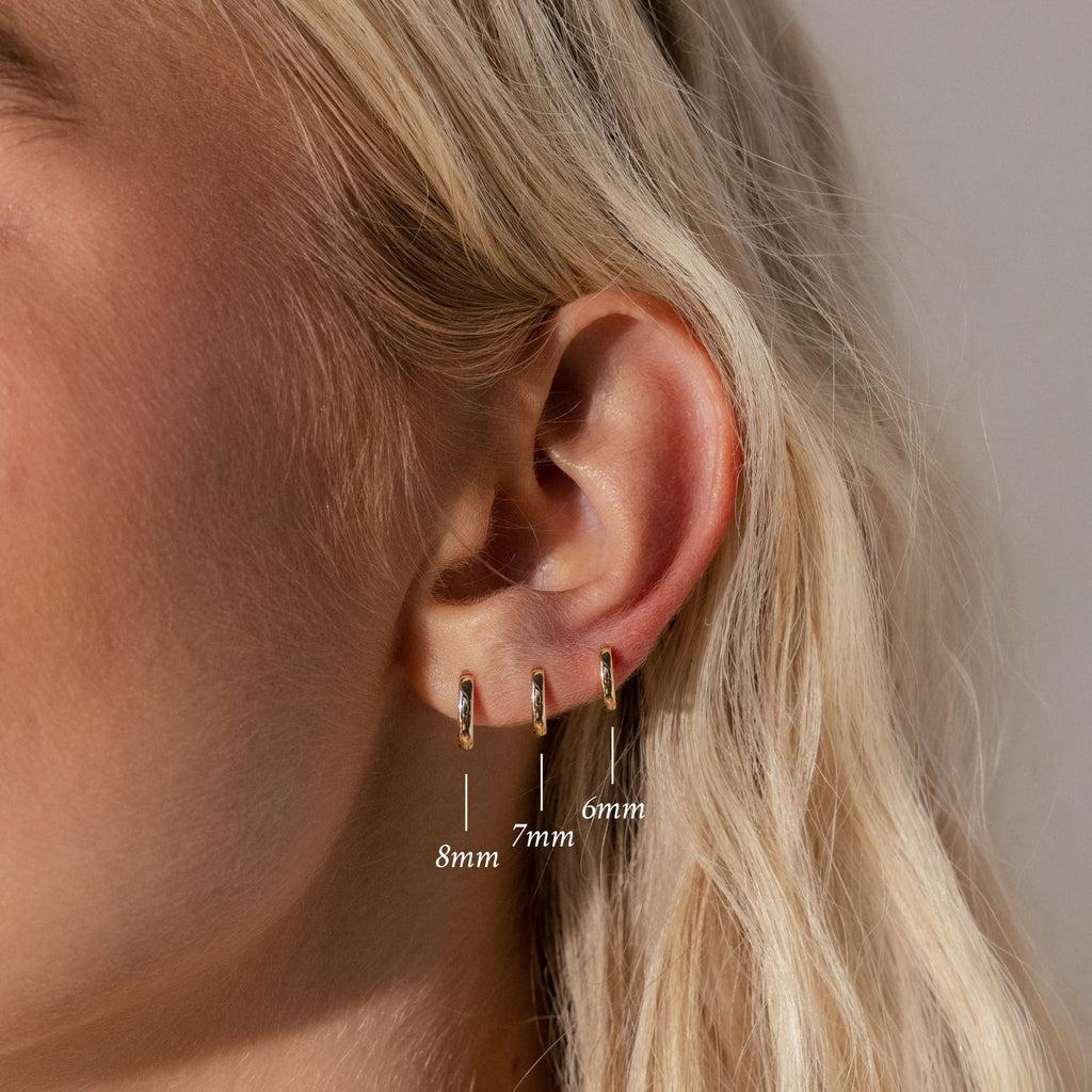 Close-up of an ear wearing the Dainty Huggies Set—three minimalist earrings in 8mm, 7mm, and 6mm sizes from left to right, perfect for everyday style.