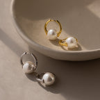 The Bold Round Pearl Hoops in Silver are displayed on a beige ceramic dish, highlighting modern jewelry with bold earrings perfect for any occasion.