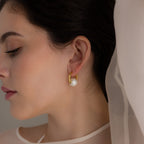 Woman with dark hair wearing Bold Round Pearl Hoops in 18K Gold, eyes closed and draped in sheer fabric.