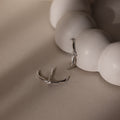 Silver ear jacket stud earrings with small diamonds on a beige surface