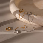 Set of gold and silver stud earrings each attached to an ear cuff on a beige stone surface