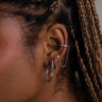 Close-up of an ear with multiple silver earrings against a blurred background