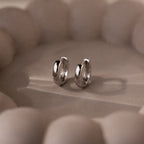 Pair of silver hoop earrings on a textured beige surface