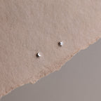 Small star and moon silver earrings on a textured beige surface