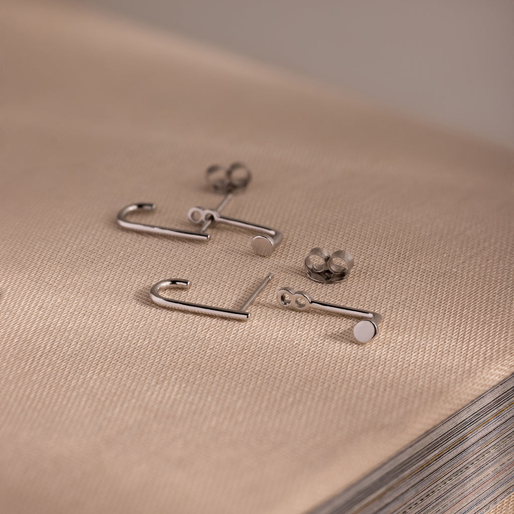 Silver jacket earrings on a textured beige surface
