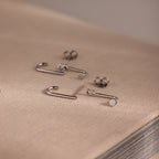 Silver jacket earrings on a textured beige surface