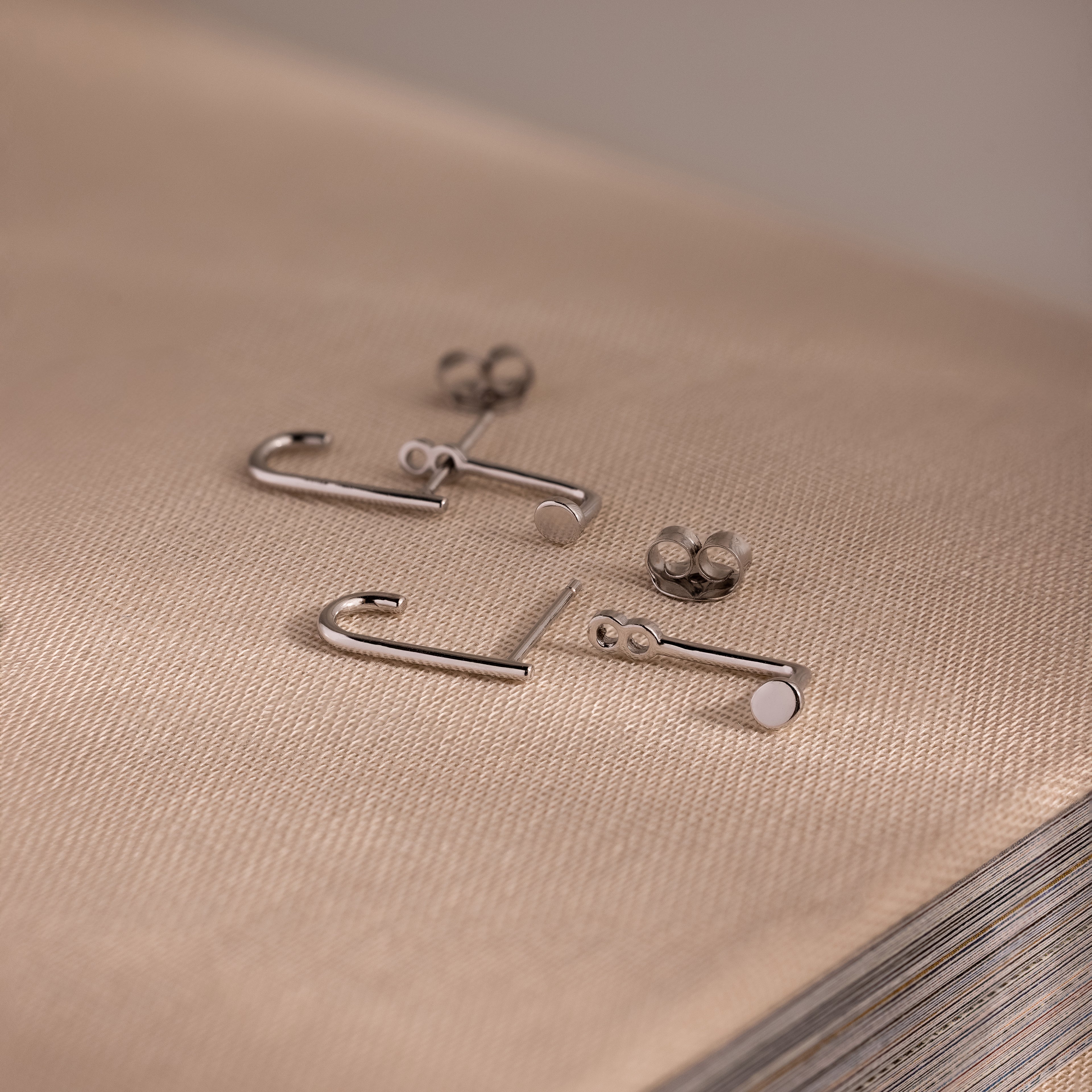 Silver jacket earrings on a textured beige surface