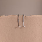 Two silver earring jackets on a beige background