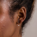 Close-up of an ear with a silver earring jacket on a neutral background