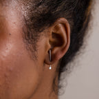 Close-up of an ear with a silver earring jacket on a neutral background