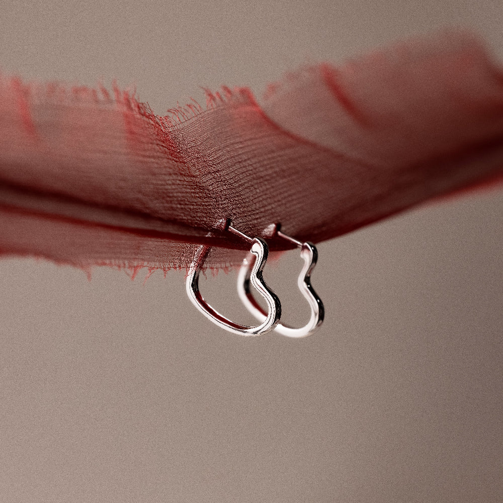 Two silver hoop earrings on a red fabric background
