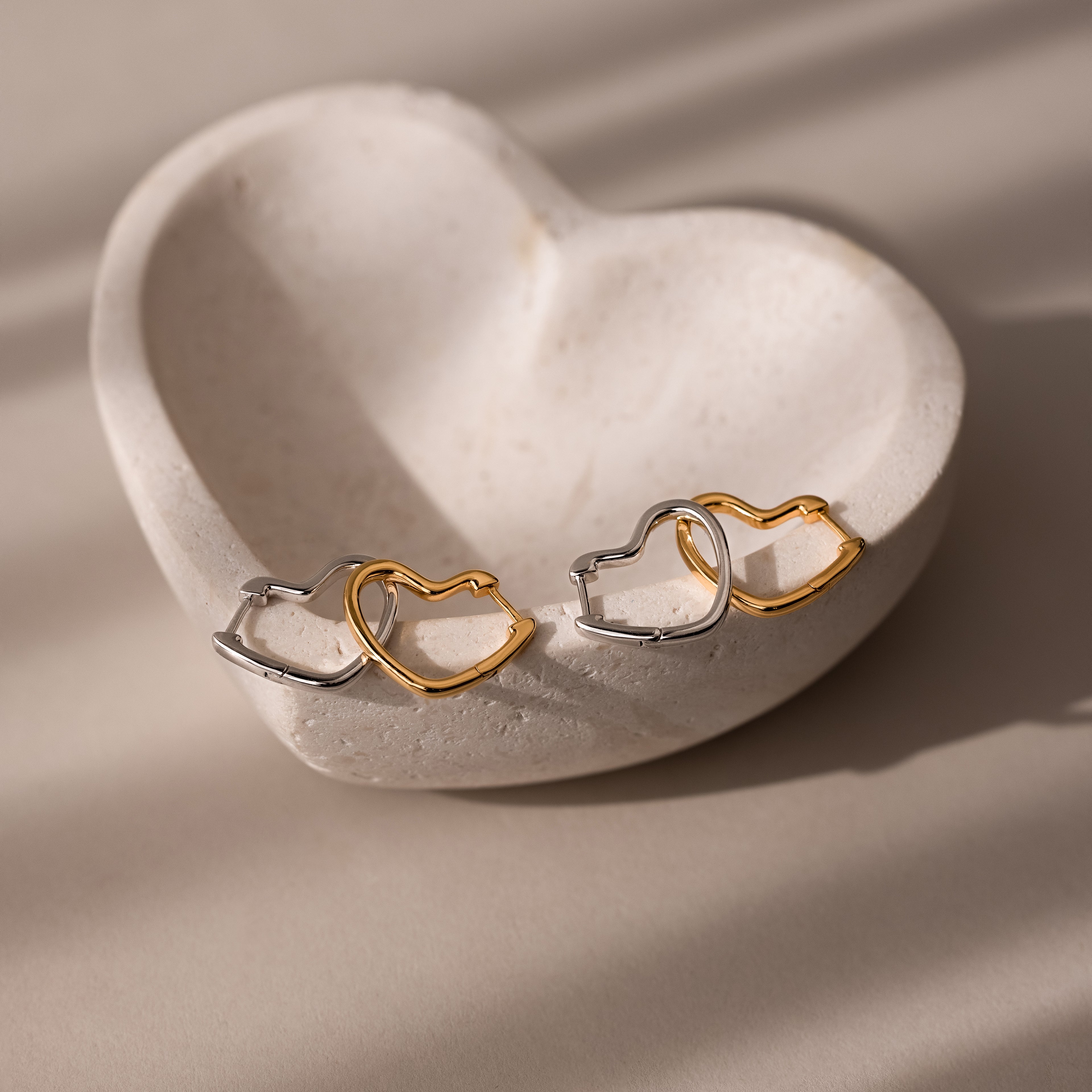 Heart-shaped earrings in gold and silver on a heart-shaped stone