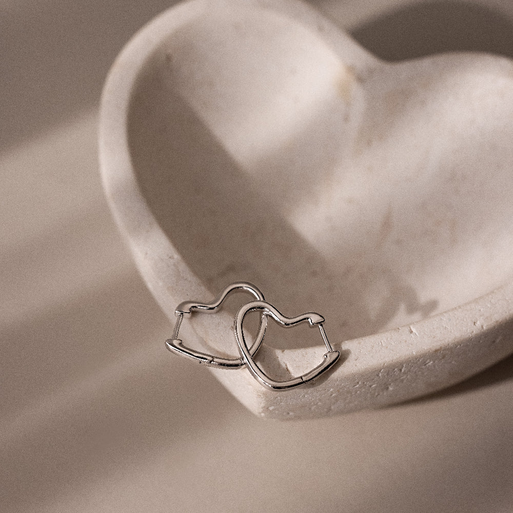 Silver heart shaped hoop earrings on a heart-shaped stone