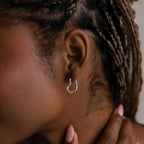 Close-up of a model with a silver heart shaped hoop earring and braided hair.