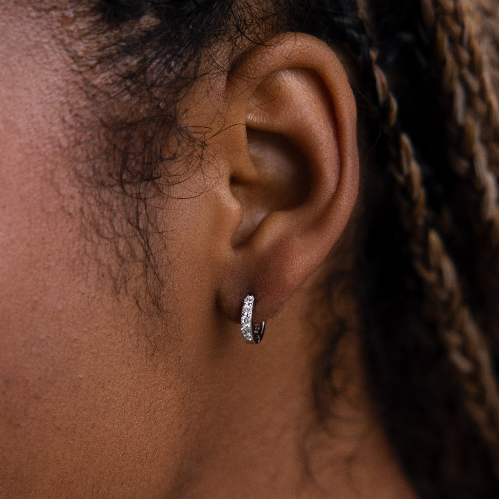 Close-up of a model wearing a silver diamond hoop earring with braided hair.