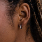 Close-up of a model wearing a silver diamond hoop earring with braided hair.