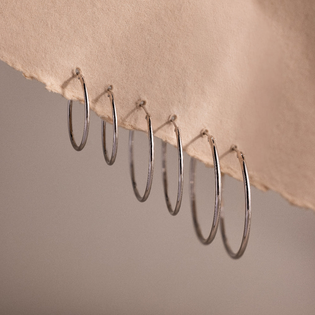 Set of silver hoop earrings on a textured beige surface