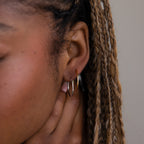 Close-up of a model with gold and silver hoop earrings and braided hair.