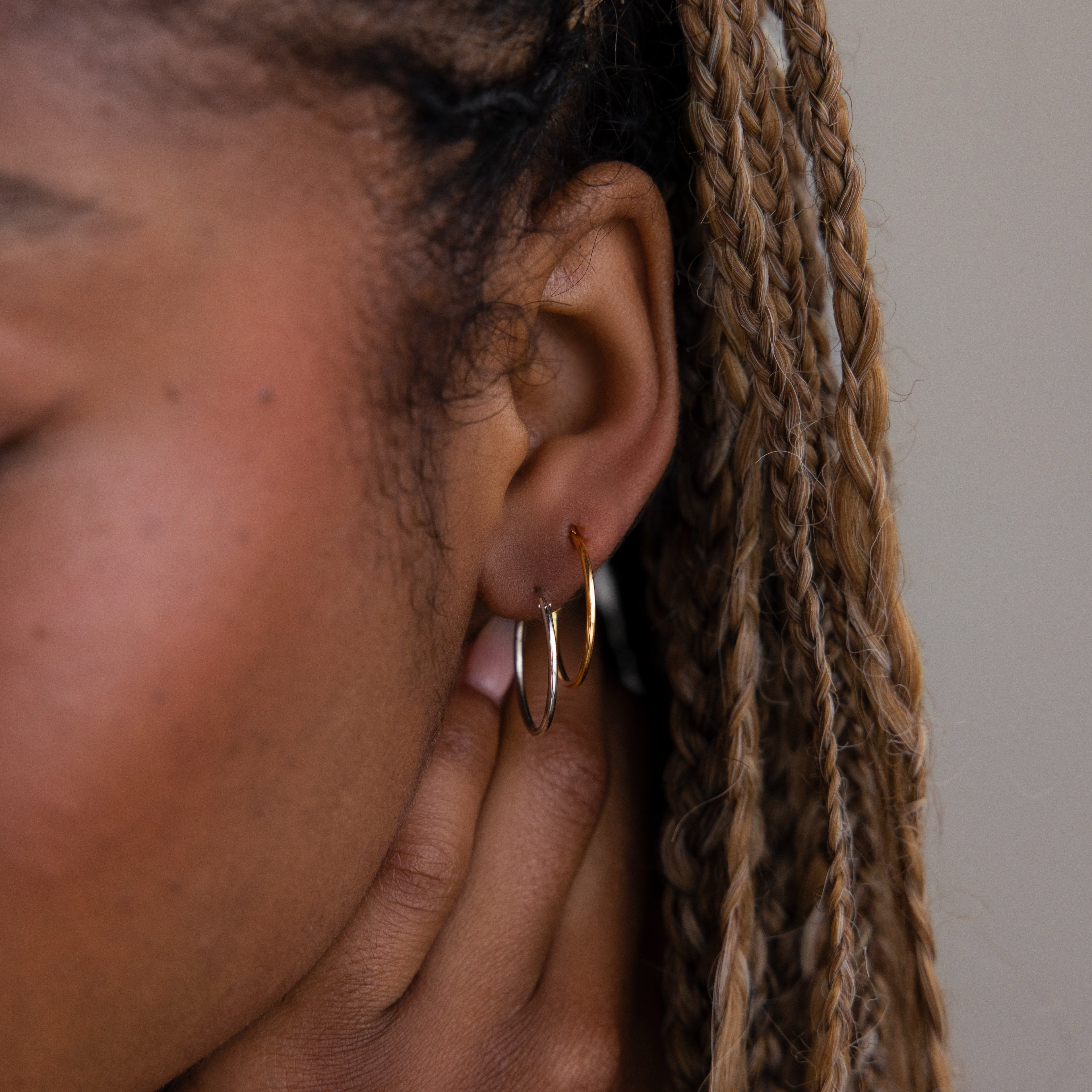 Close-up of a model with gold and silver hoop earrings and braided hair.