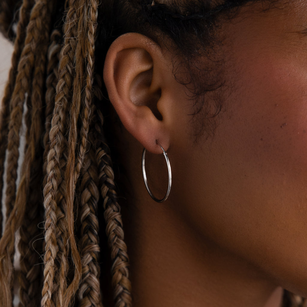 Close-up of a model with a silver hoop earring and braided hair.