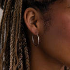 Close-up of a model with a silver hoop earring and braided hair.