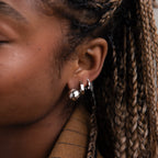 Close-up of a model with multiple silver earrings and braided hair.