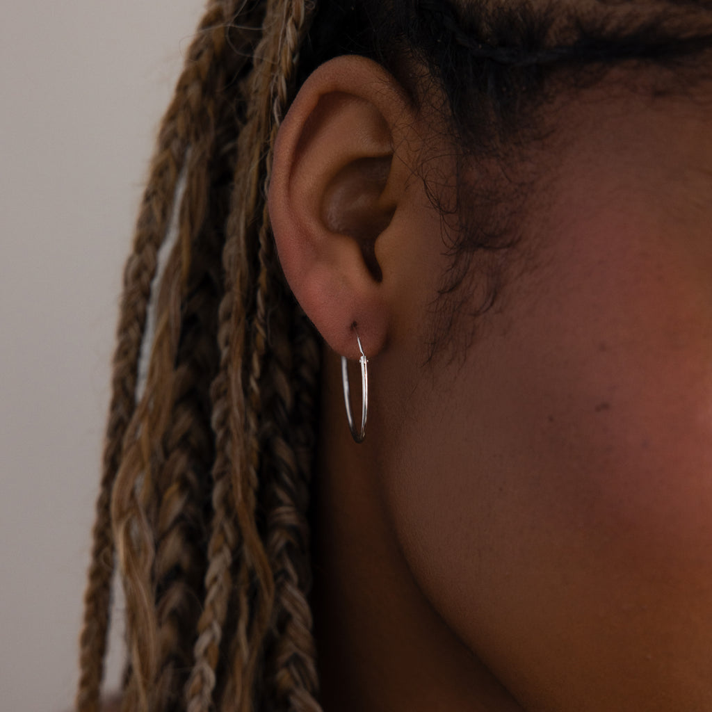 Close-up of a model with a silver hoop earring and braided hair.