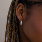 Close-up of a model with a silver hoop earring and braided hair.