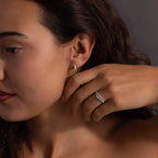 A woman touches her face while wearing the Art Deco Diamond Earrings & Ring Set in Sterling Silver.