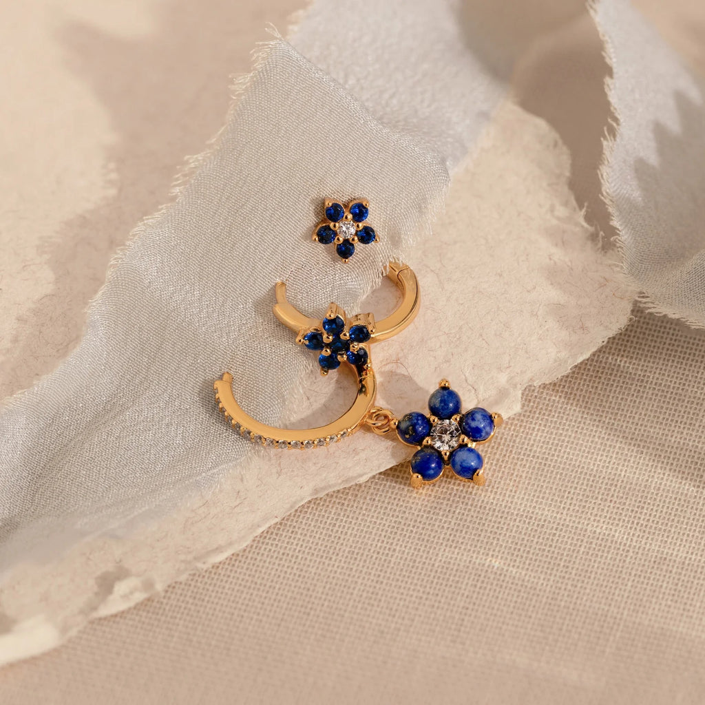 The Sapphire Flower Earrings Set features gold earrings with blue stones and diamonds, ideal for adding a touch of elegance to your jewelry collection.