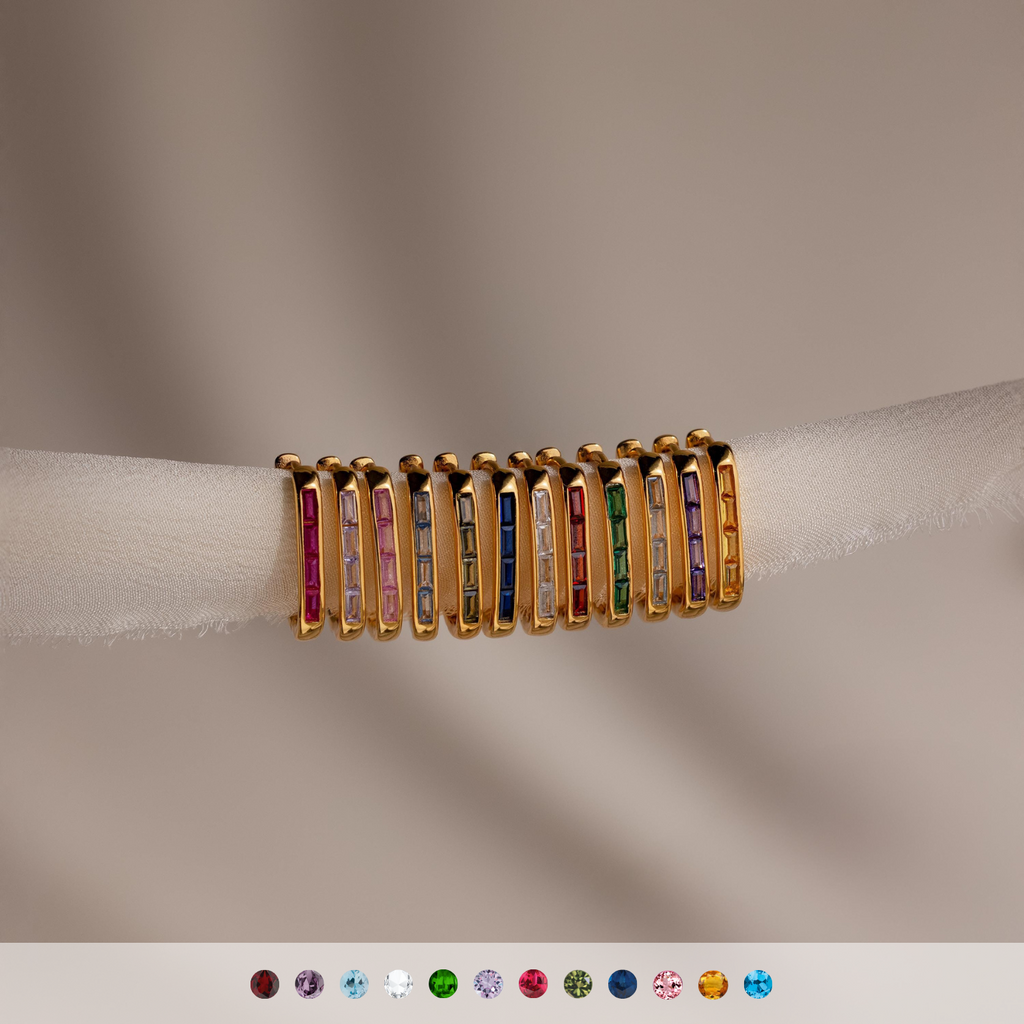Nine Baguette Birthstone Link Earrings with customizable gemstones and colorful designs are displayed on soft, sheer fabric, with gemstone icons below.