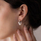 Close-up of a woman with her hand near her ear, wearing elegant Pearl Chandelier Huggies featuring delicate pearl clusters.