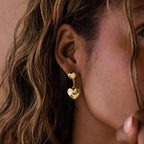 Close-up of a woman's ear wearing Duo Heart Drop Studs, highlighting their elegant double heart drop design.