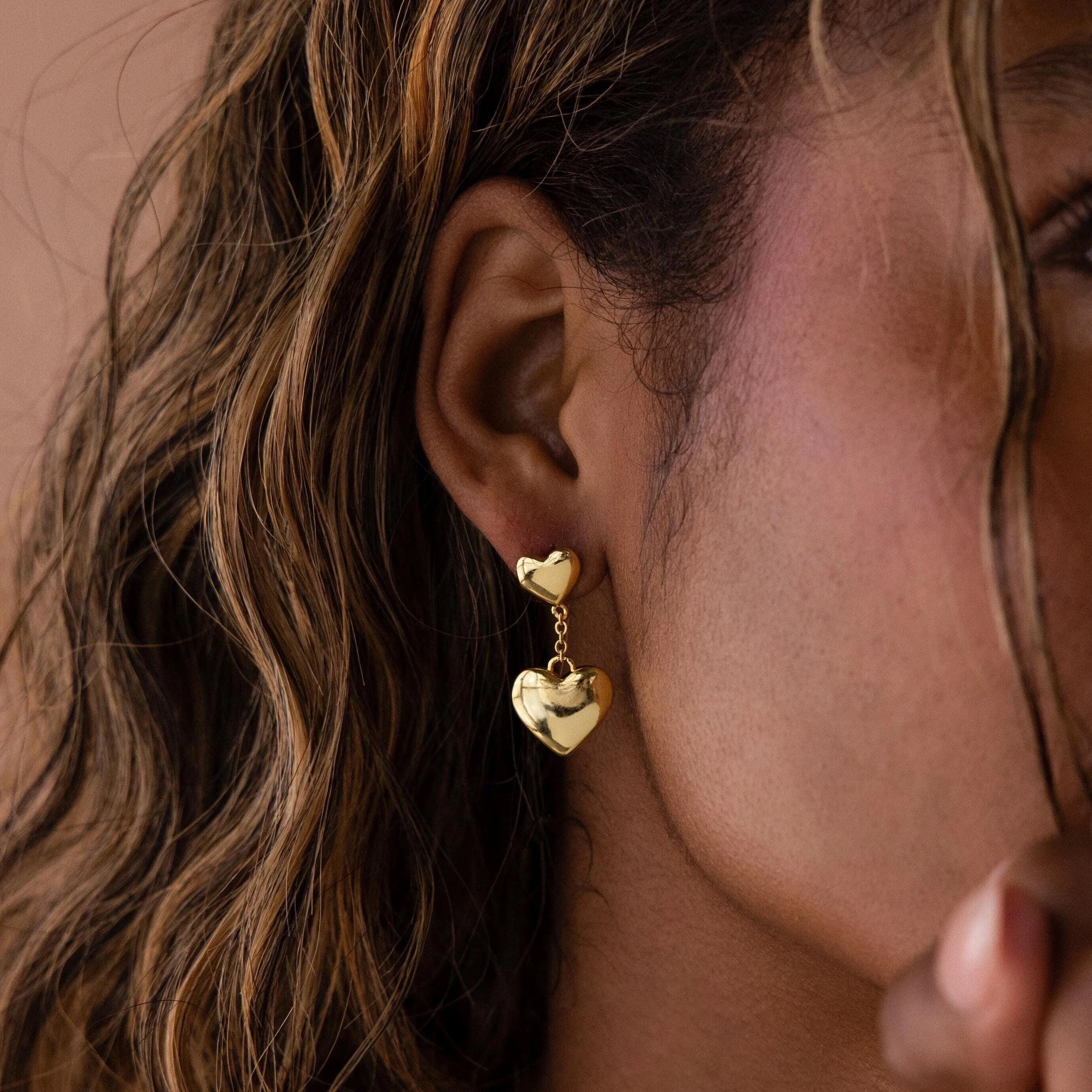 Close-up of a woman's ear wearing Duo Heart Drop Studs, highlighting their elegant double heart drop design.