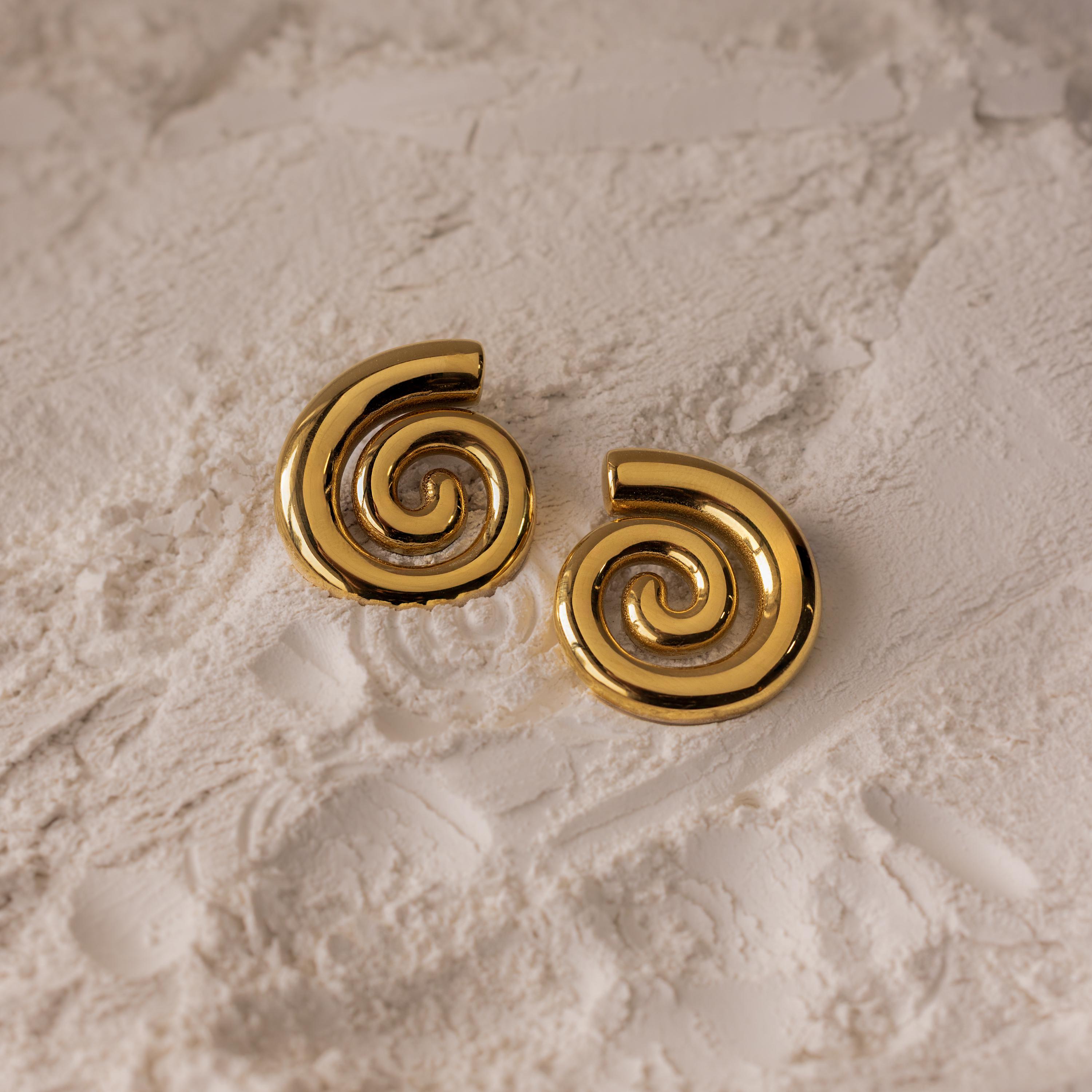 Bold Spiral Stud Earrings rest elegantly on a textured white surface, creating a subtle yet stylish statement.