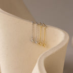 Close up of a pair of silver starburst chain stud earrings and a pair of gold starburst chain stud earrings hanging side by side on a ceramic dish.