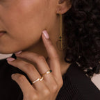 Woman with curly hair wears Agate Threader Earrings, touching her face with manicured nails and showcasing modern style.