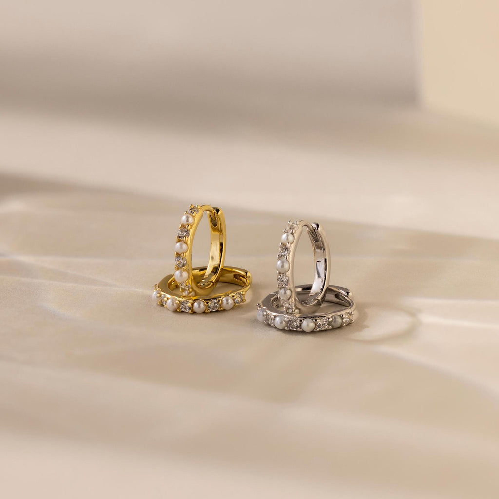 The Pave Pearl Huggies are elegant hoop earrings in gold and silver, offering timeless sophistication.