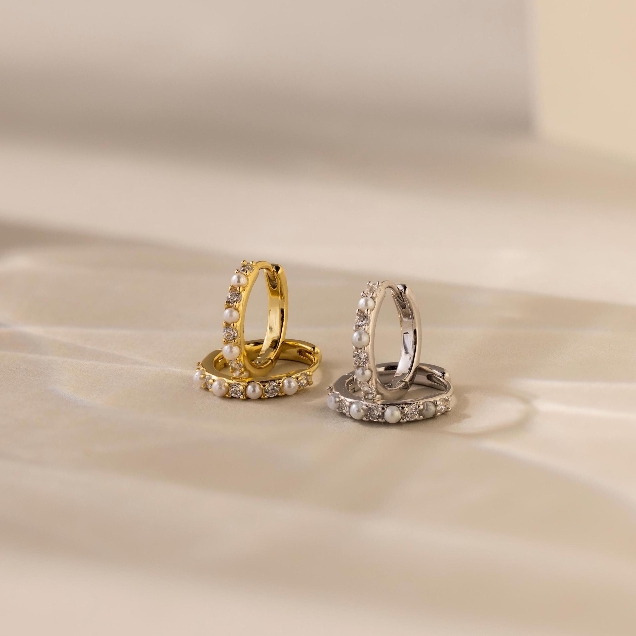 The Pave Pearl Huggies are elegant hoop earrings in gold and silver, offering timeless sophistication.