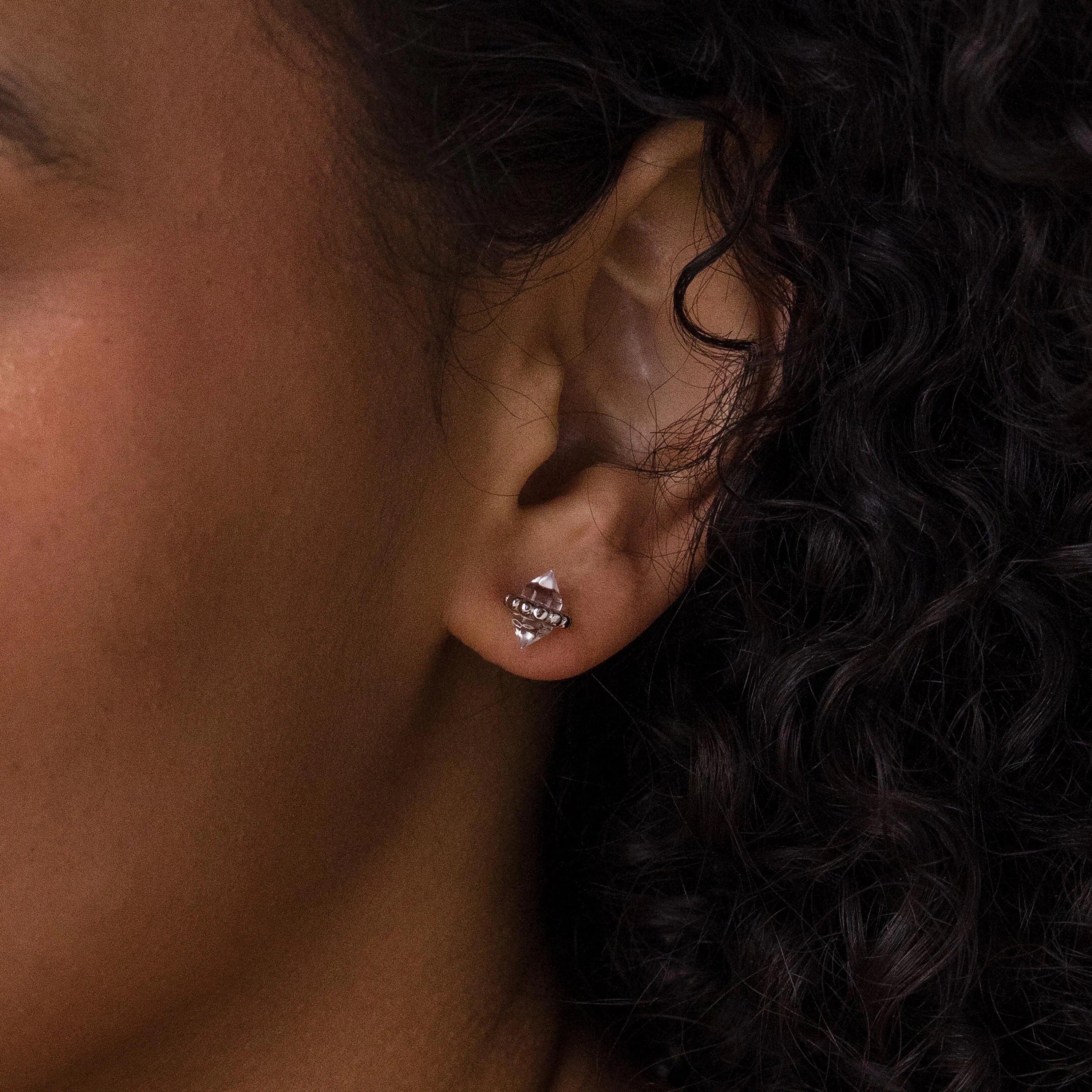 A close-up of a woman's ear adorned with luminous Beaded Herkimer Studs, delicate earrings that catch the light beautifully.