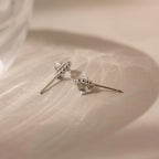 The Beaded Herkimer Studs, featuring clear faceted accents, rest on a softly textured beige surface, giving these silver earrings a luminous shine.