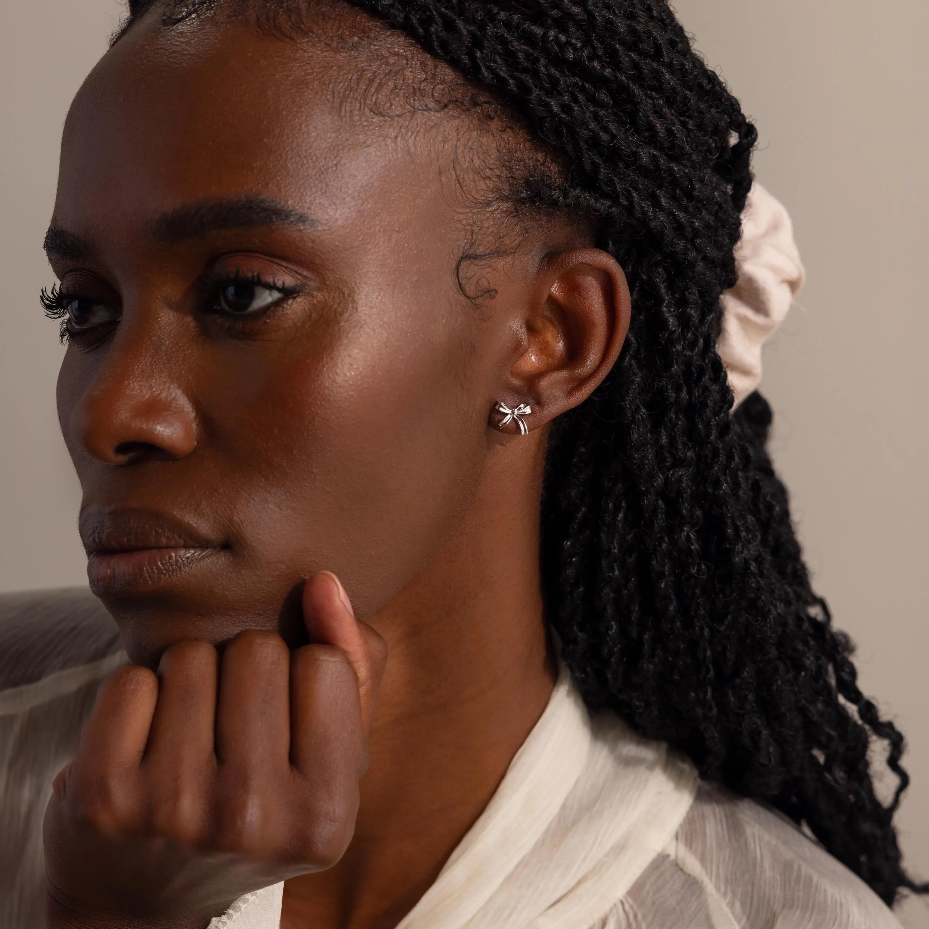 A portrait of a woman wearing silver bow stud earrings.